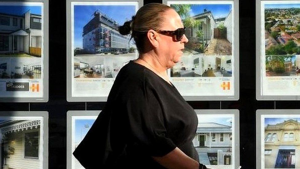 Woman walking by estate agent window