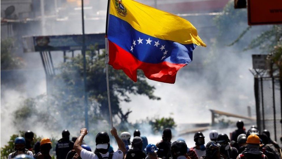 A demonstrator waves a Venezuelan flag during riots at a march to state Ombudsman's office in Caracas, Venezuela May 29, 2017.