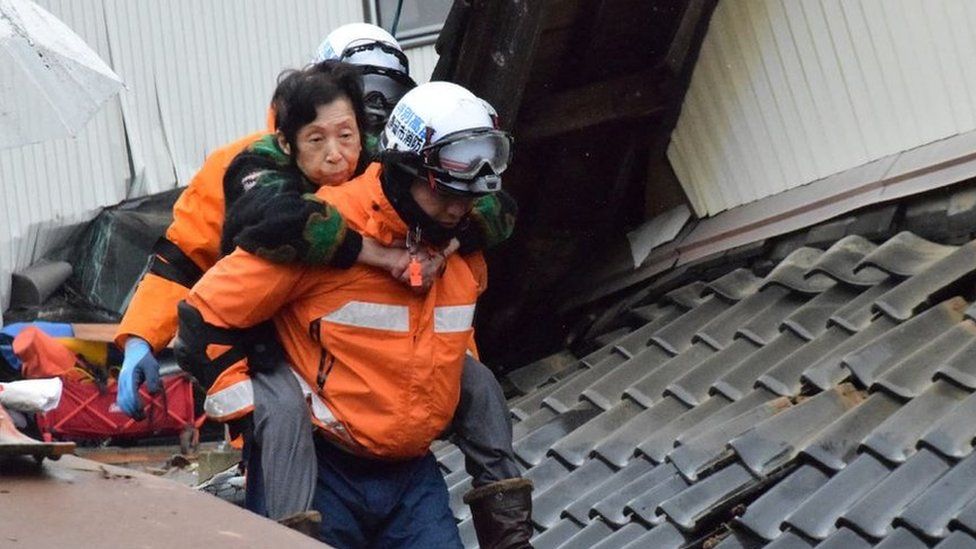 Elderly woman is carried on the back of a rescue worker in Suzu, Japan