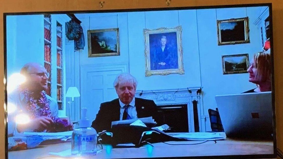 Une photo de Boris Johnson à côté de deux autres personnes dans un bureau