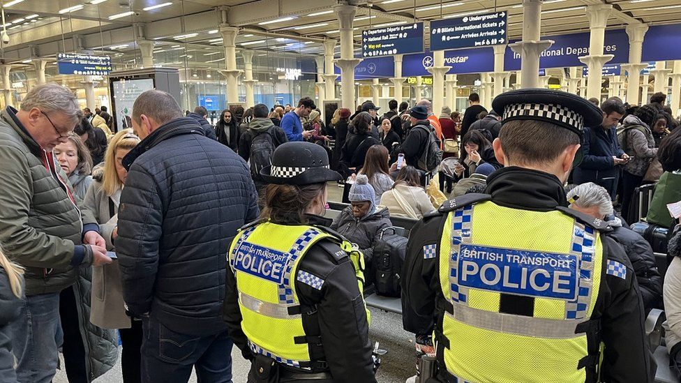 British Transport Police officers watch as passengers wait at the Eurostar entrance in St Pancras International station, London