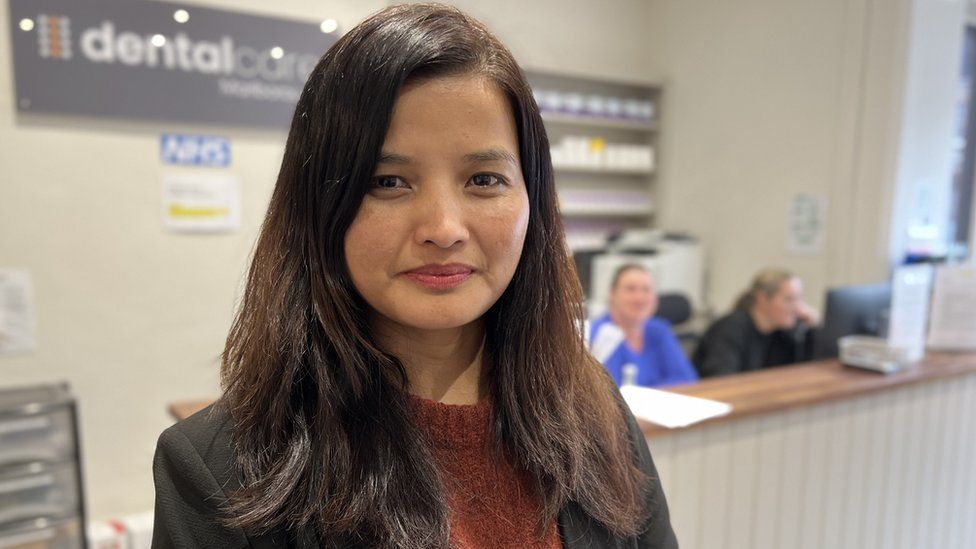 Sashi Gurung, the practice manager, looks at the camera, with the front desk behind her.