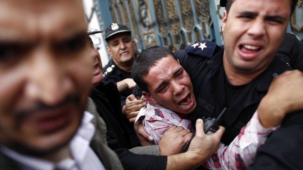 Egyptian policemen protect an opposition supporter during clashes with Muslim Brotherhood supporters outside the Ittihadiya presidential palace in Cairo (5 December 2012)