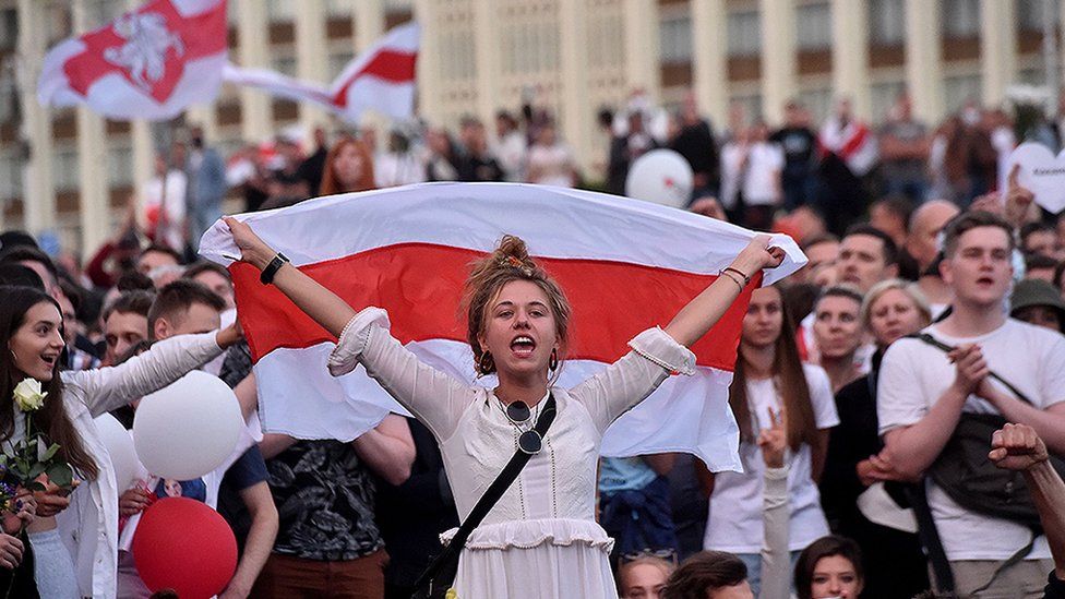 A woman shouts as she holds a Belarus flag