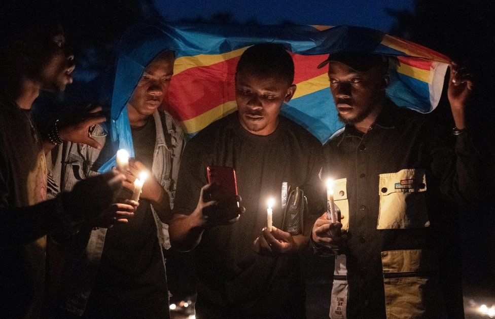 People hold candles and the Congolese national flag a a memorial ceremony.