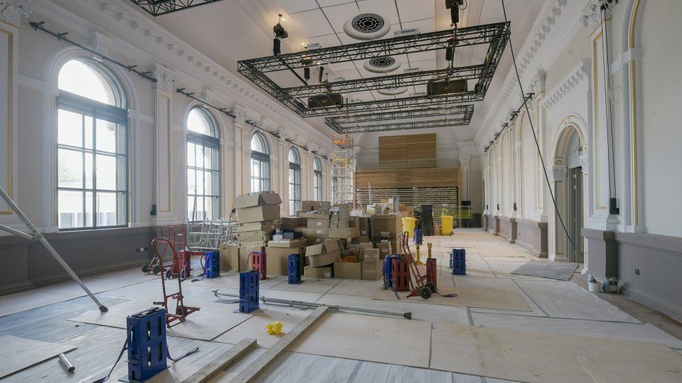 A room with large arched windows and theatre lighting going through renovation.