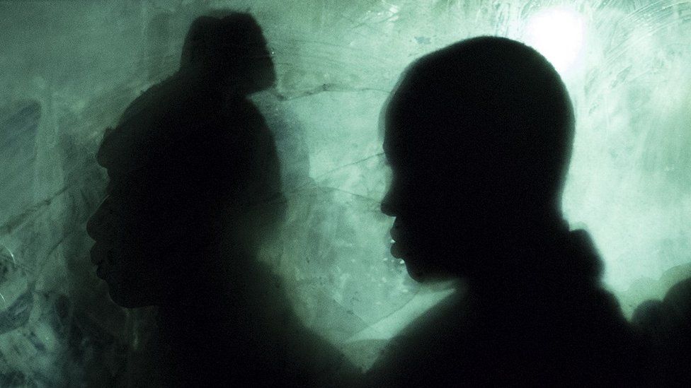 Silhouettes of two people inside a bus waiting to be transferred