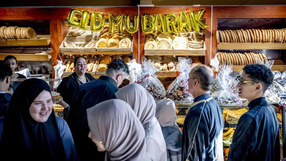 People inside a bakery, with a sign saying 'Eid Mubarak' in Rotterdam, the Netherlands