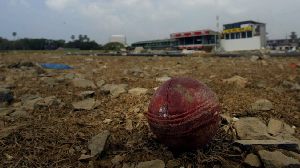 A cricket ball sits on the ground of the devastated stadium