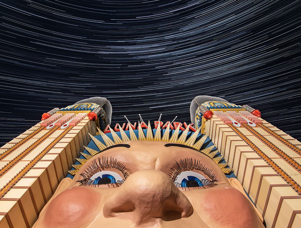 An image showing a park entrance featuring a large face with stars in the sky above