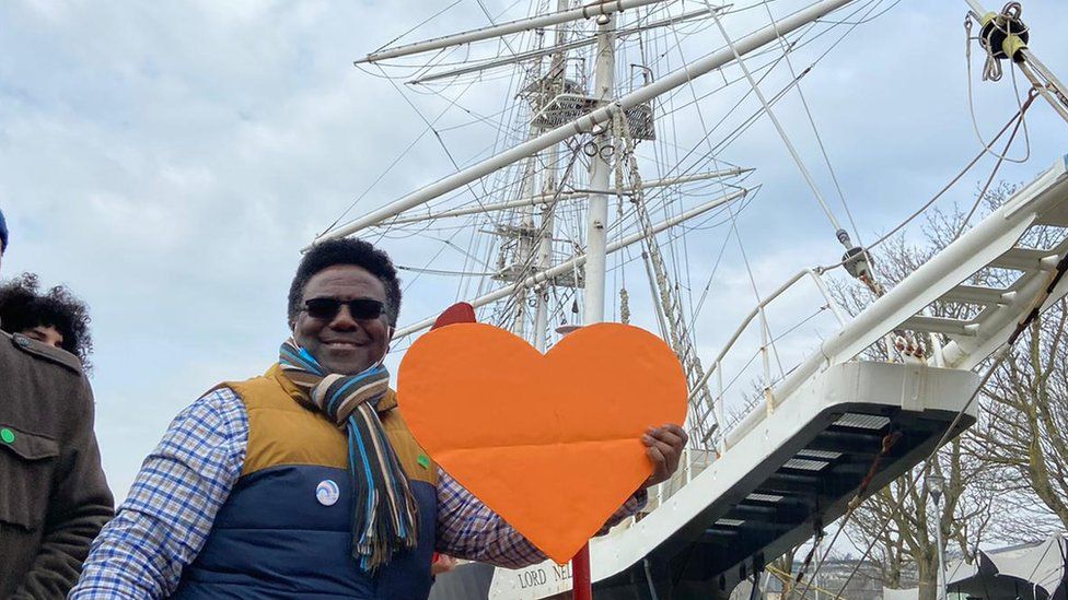 A supporter holding an orange heart to show his support for asylum seekers