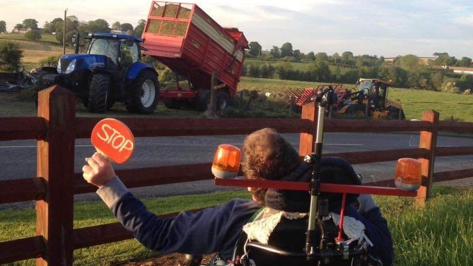Jonathan Turtle uses a table tennis bat to direct his brother as he unloads silage