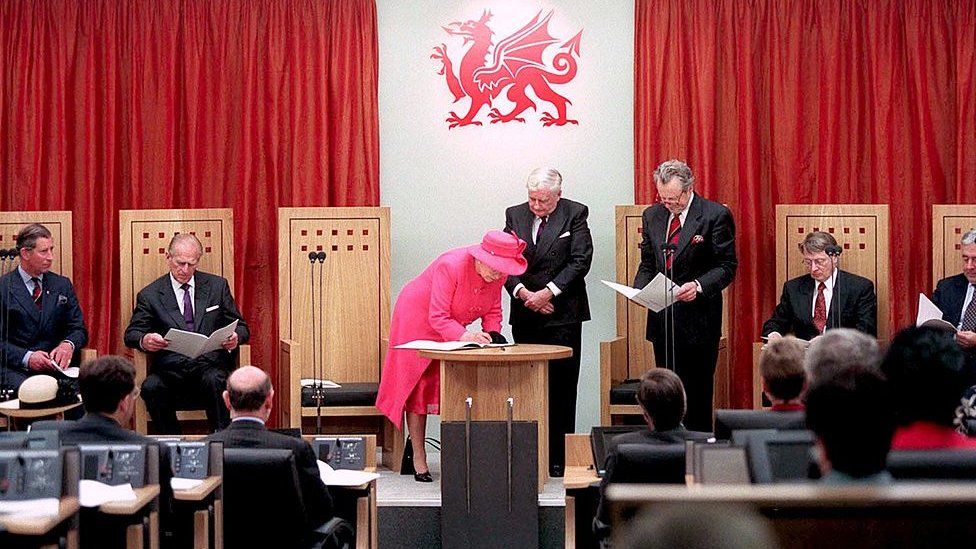 Queen Elizabeth signs a special edition of the 'first words' Act before presenting the bound volume to the Welsh Assembly and its members in 1999 as a symbol of the new relationship between Westminster and Wales