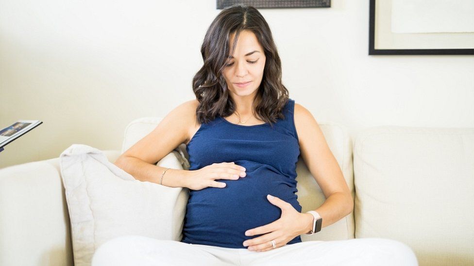 Pregnant woman touching and looking at her belly