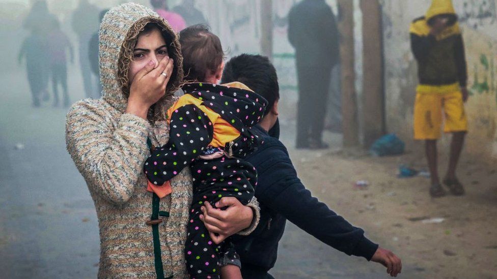 A woman holding a child pictured after an Israeli strike in Rafah in the southern Gaza Strip on 23 November