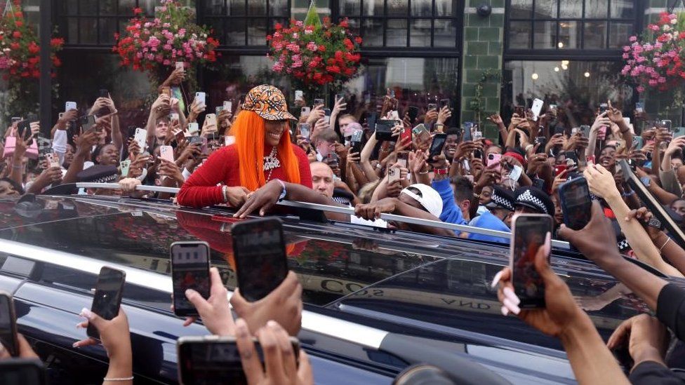 US rapper Nicki Minaj smiles for fans who surround her car in Camden