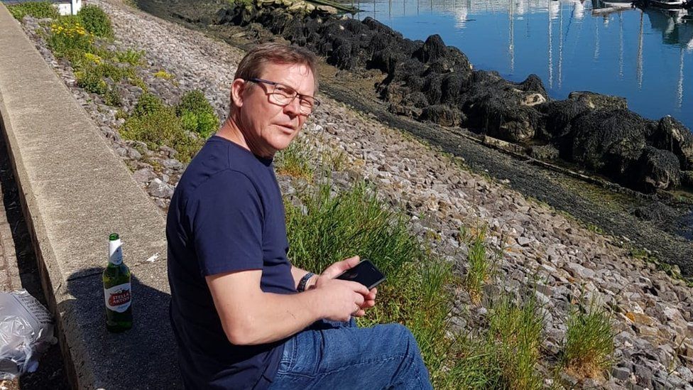 Paul English sitting on the edge of a marina
