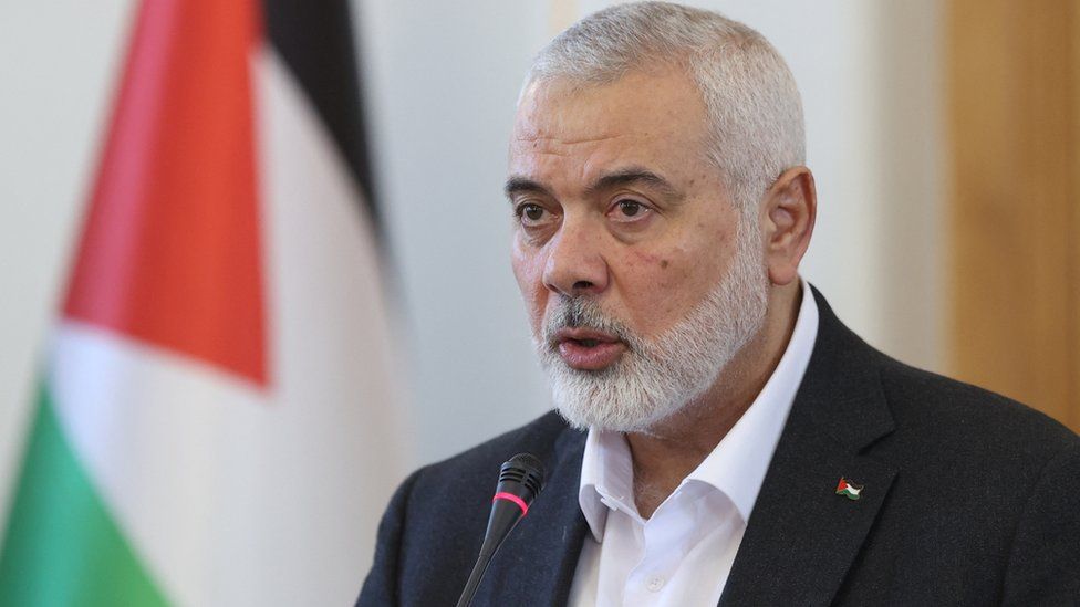 Hamas' top leader Ismail Haniyeh speaking into a microphone with the Palestinian flag behind him