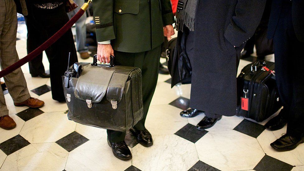 A military aide carries the nuclear football, with the United States' nuclear launch codes