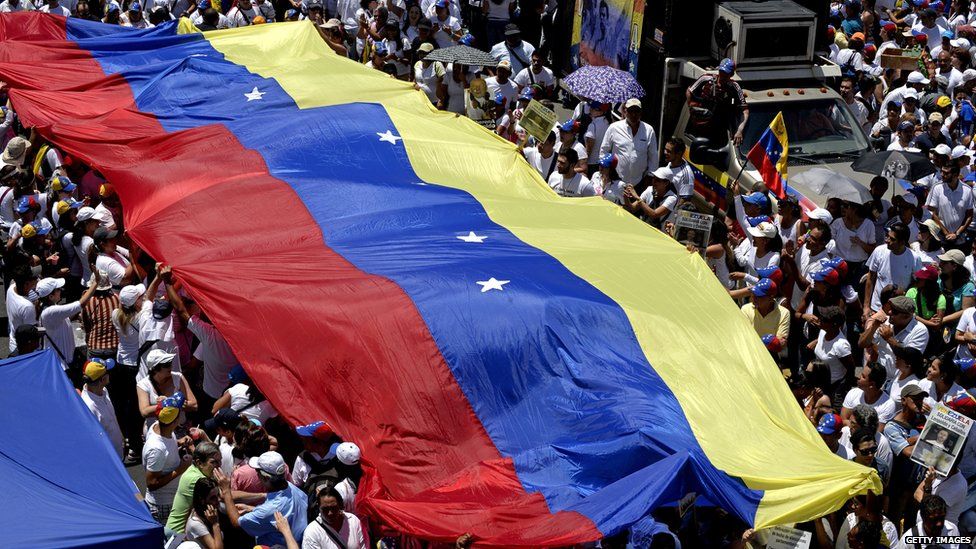 Crowds of people holding a huge Venezuelan flag