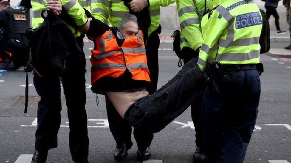 Police officers carry an Insulate Britain activist during a protest in London