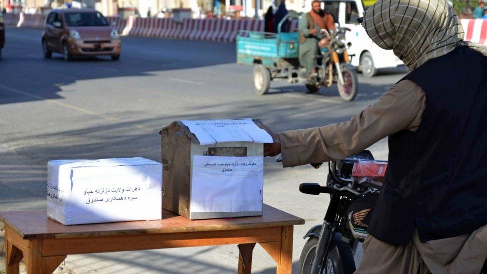 Автомобилисты кладут деньги в ящики для пожертвований жертвам землетрясения в Кандагаре, Афганистан, 8 октября 2023 г.