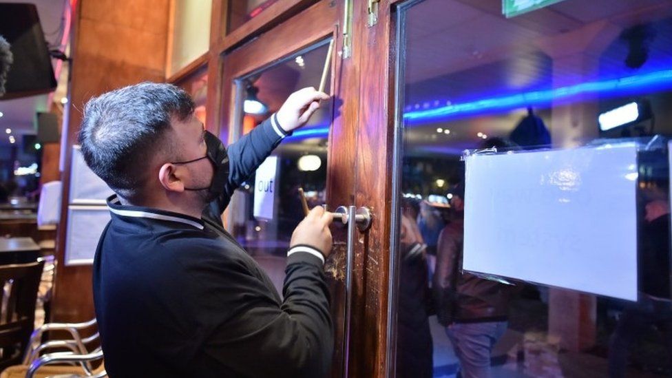 A worker shuts the doors in a bar in Bristol city centre, ahead of a national lockdown for England from Thursday