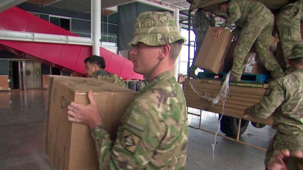 Defence force staff pass along boxes of essential items for evacuation centres