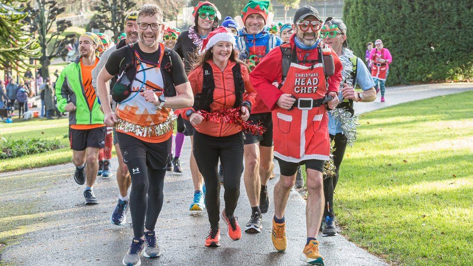 Andy Mutter running with a group of supporters in Christmas-themed outfits