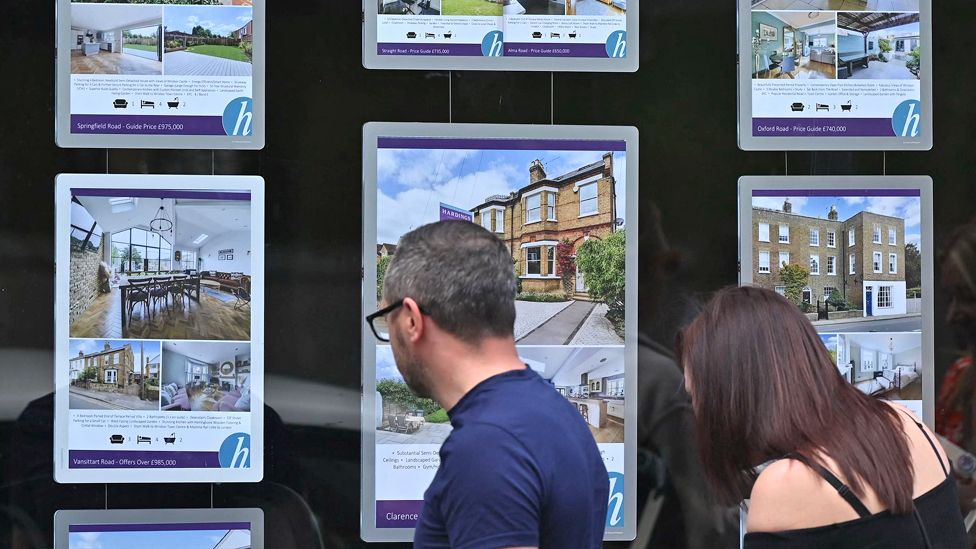 Man and a woman look at an estate agent's window