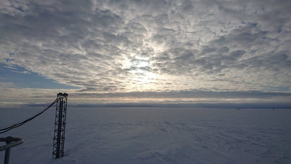 A vast scene of white snow. The clouds are lumpy and white, with the sun shining through