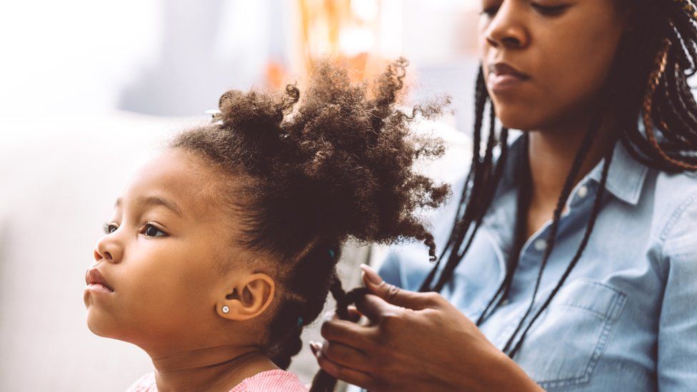 A mother plaiting her daughter's hair - generic