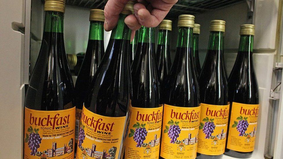 A customer reaches for a bottle of Buckfast out of an off-licence fridge