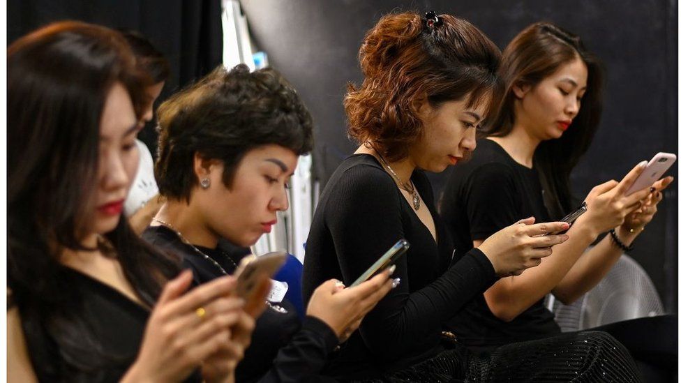 Women looking at their mobile phones at a studio in Hanoi.