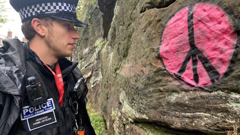A heritage crime officer examines graffiti sprayed onto ancient remains in Chester, Cheshire