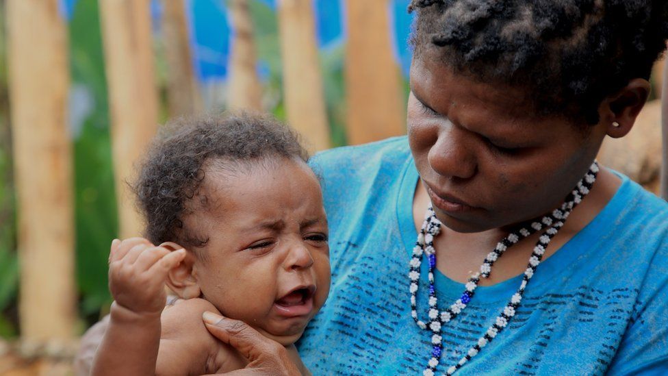 Jubiana Kogeya holding her baby, who is crying