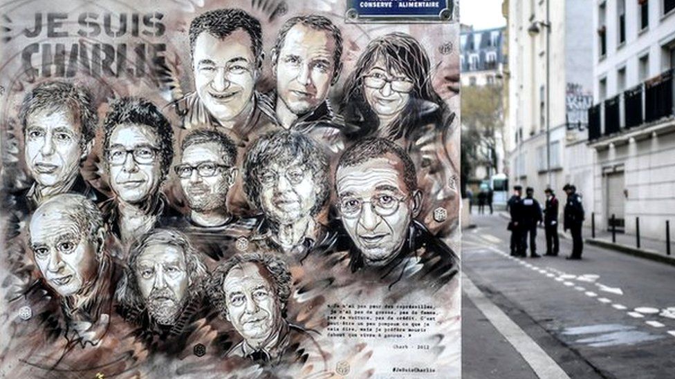 Policemen are seen next to a painting in tribute to members of Charlie Hebdo newspaper