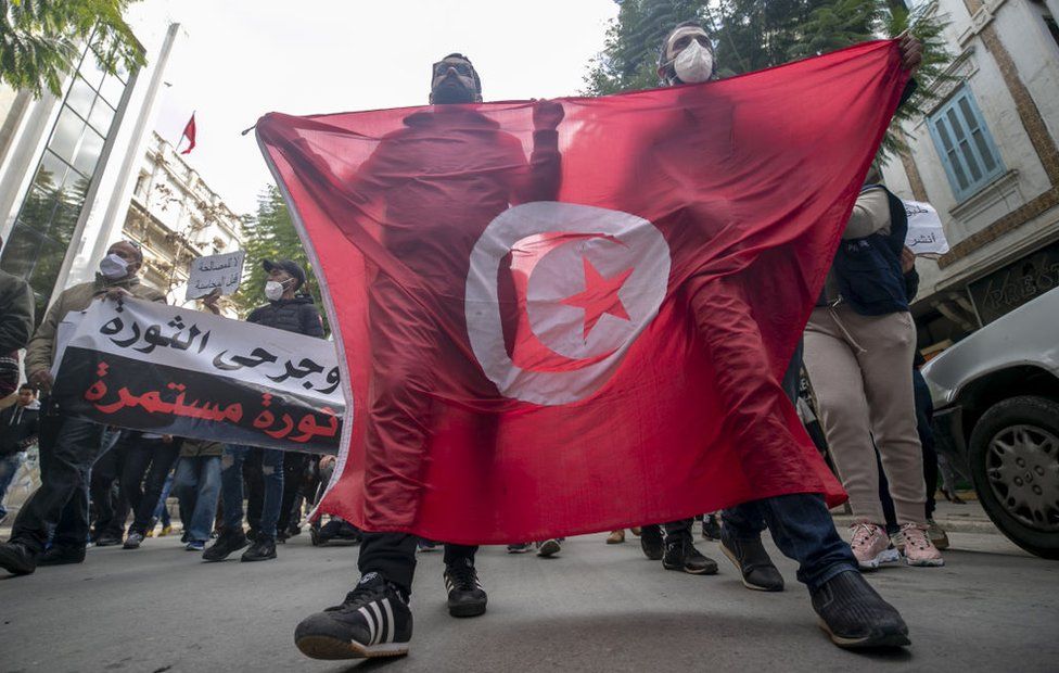 Группа тунисцев устраивает демонстрацию, требуя, чтобы имена тех, кто погиб в ходе массовых публичных демонстраций 14 января 2011 года, свергнувших бывшего президента Туниса Зина эль-Абидина Бен Али, были внесены в список мучеников во время 10-й годовщины Туниса. Революция в Тунисе, Тунис, 14 января 2021 года.