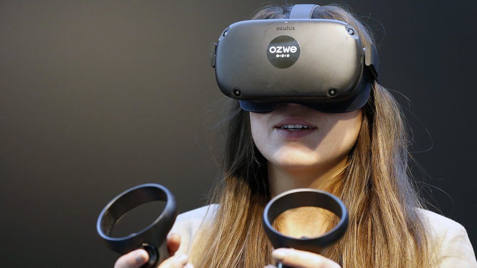 A woman wears a black first-generation Oculus Quest headset