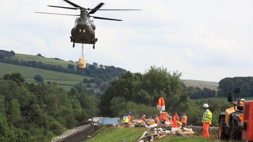 Chinook helicopter carries aggregate as worker looks on