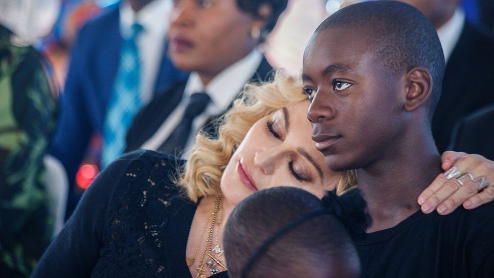 US pop star Madonna (left) rests her head on the shoulder of her adopted son David Banda during the opening ceremony of the Mercy James Children's Hospital at Queen Elizabeth Central Hospital in Blantyre, Malawi, on 11 July 2017.