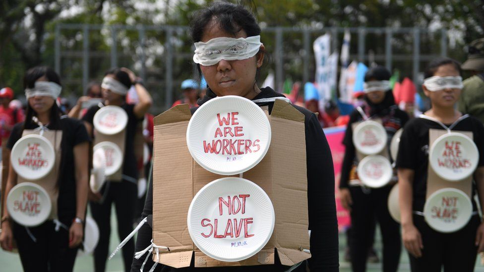 Migrant workers are seen wearing blindfolds and wearing cardboard signs during the May Day rally in Hong Kong