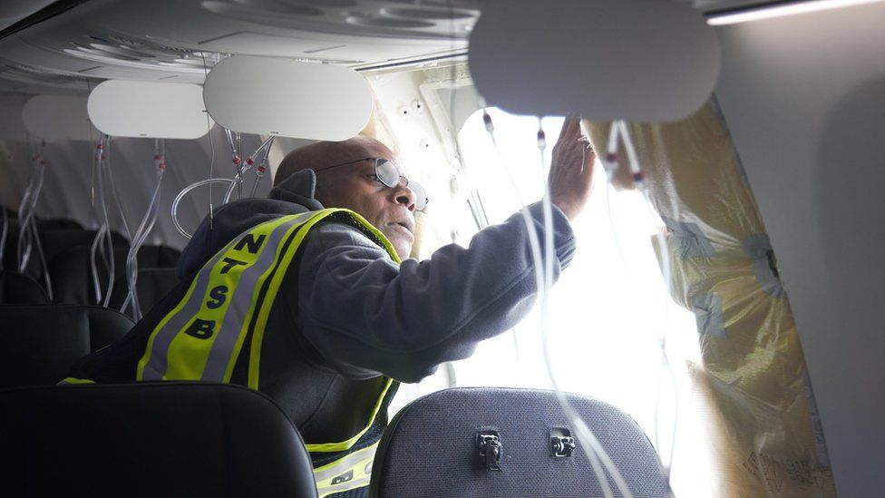 A National Transportation Safety Board investigator surveys the broken window panel, in an image from the investigation taken two days after the incident in January
