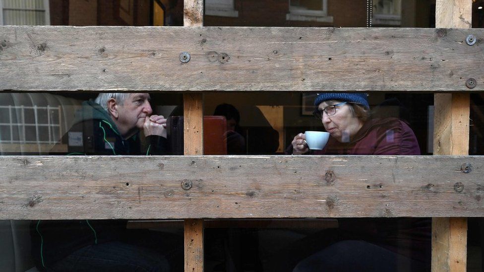 A couple sit inside a boarded-up coffee shop ahead of the annual Royal Shrovetide football match
