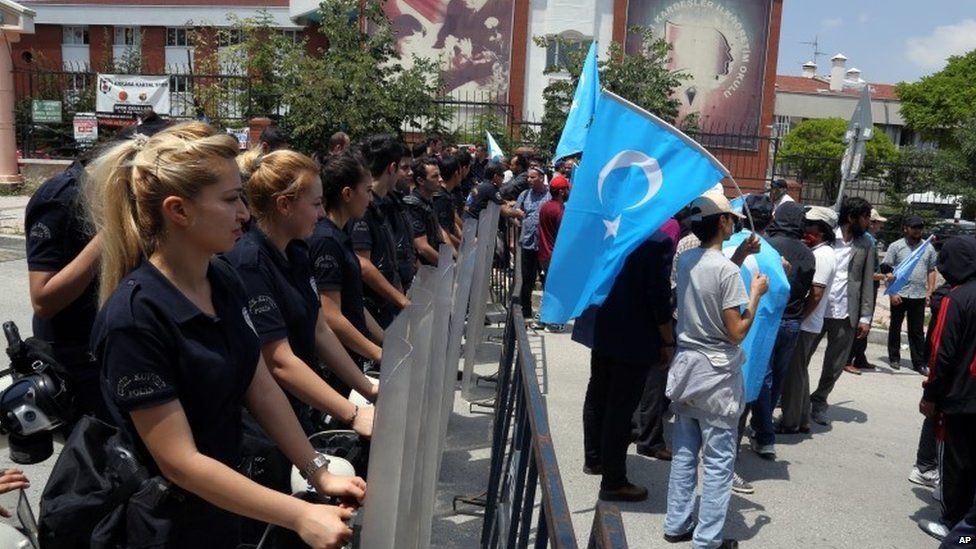Riot police stand as a group of Uighur protesters demonstrate outside the Thai embassy in Ankara