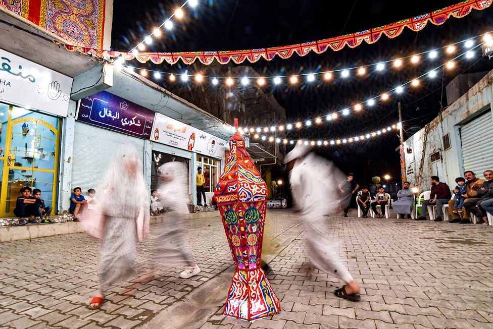Children dance around a lantern in the old town of Iraq's northern city of Mosul