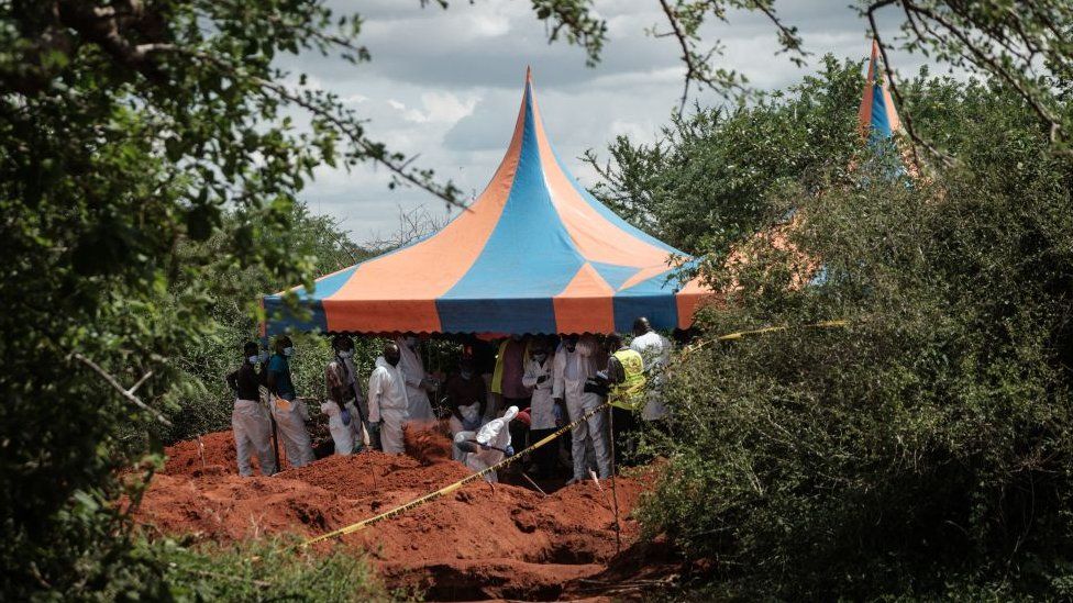 Workers take shelter while digging the ground to exhume bodies from the mass-grave site in Shakahola