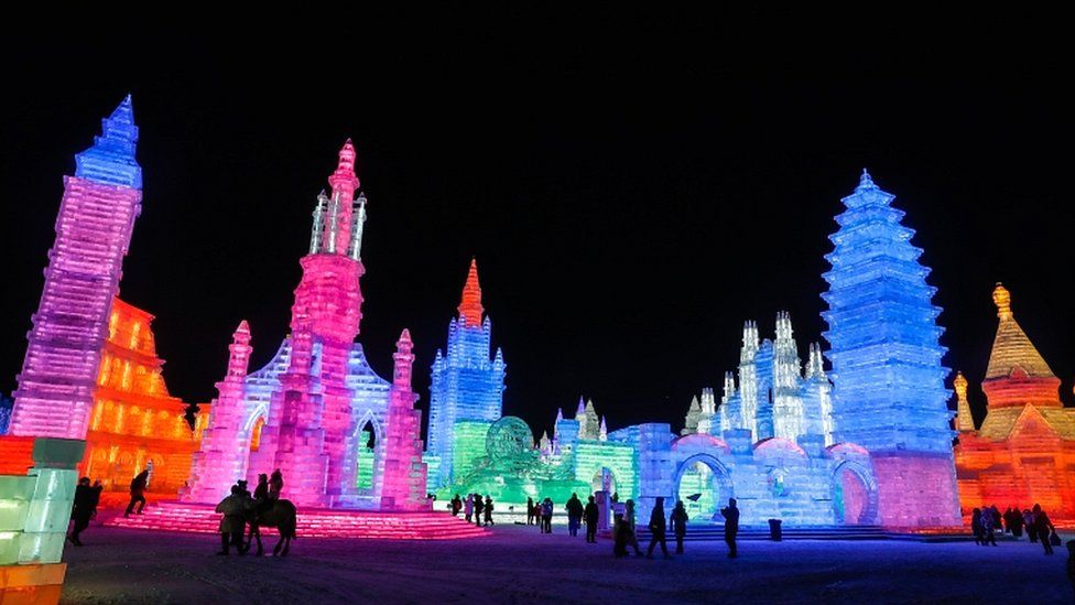 As pessoas visitam esculturas de gelo iluminadas por luzes coloridas no Ice and Snow World durante o Festival Internacional de Escultura de Gelo e Neve de Harbin em 4 de janeiro de 2019