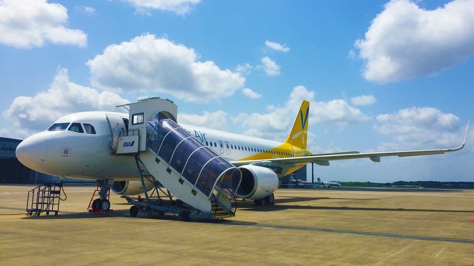 A Vanillia Air plane parked on airport tarmac, with a covered stairway leading to the open front door