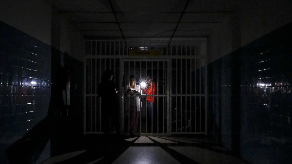 People stand on a dark corridor at Miguel Perez Carreno hospital, in Caracas